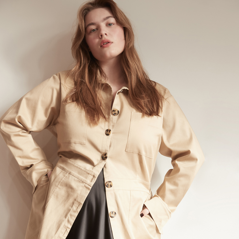 plus size woman in beige chore jacket and grey trousers